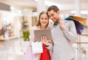 couple with tablet pc and shopping bags in mall